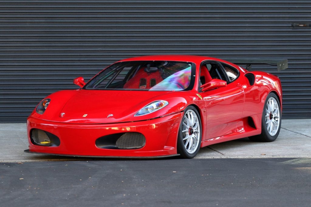 Red Ferrari F30 parked in front of a garage door