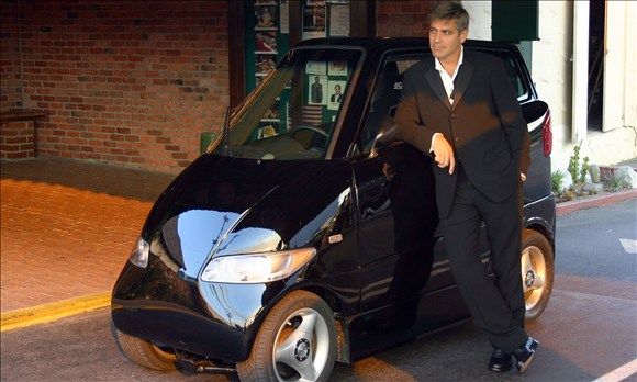 George Clooney leaning on Tango T600 car.